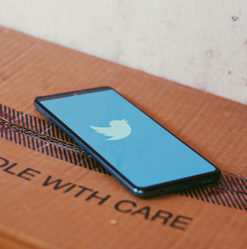 Phone with the Twitter Logo on the screen on top of a box
